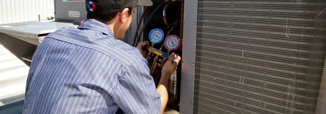 HVAC technician servicing a condenser unit in Central Point